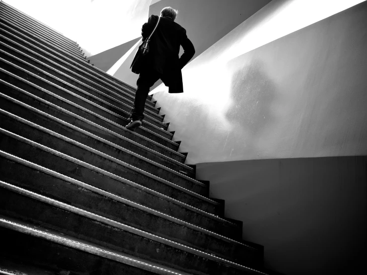 an older man walking down a set of stairs in front of some concrete walls