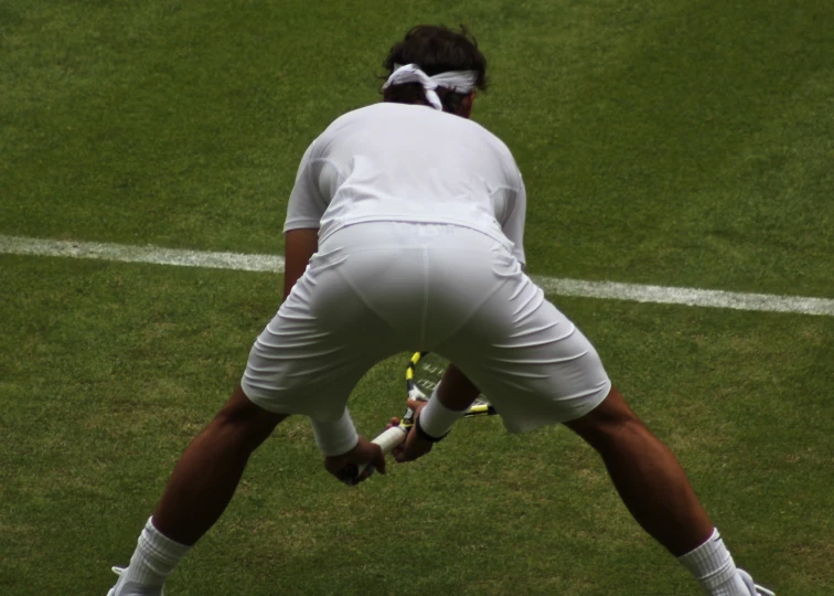 a tennis player bent down on a grass court