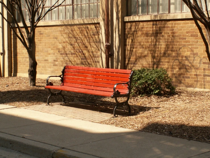 an empty bench in front of a brick wall