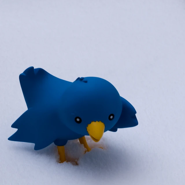 a small toy blue bird in the snow