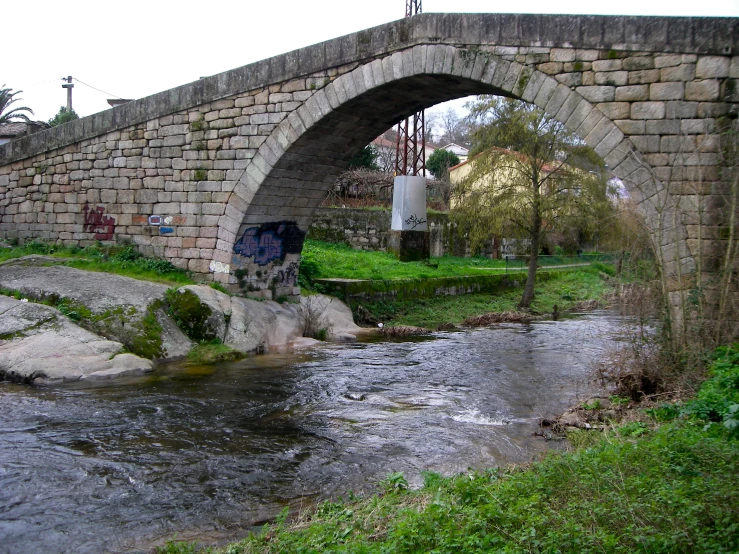 an old stone bridge with graffiti on the sides