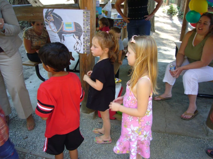 two little children are talking to others by a poster