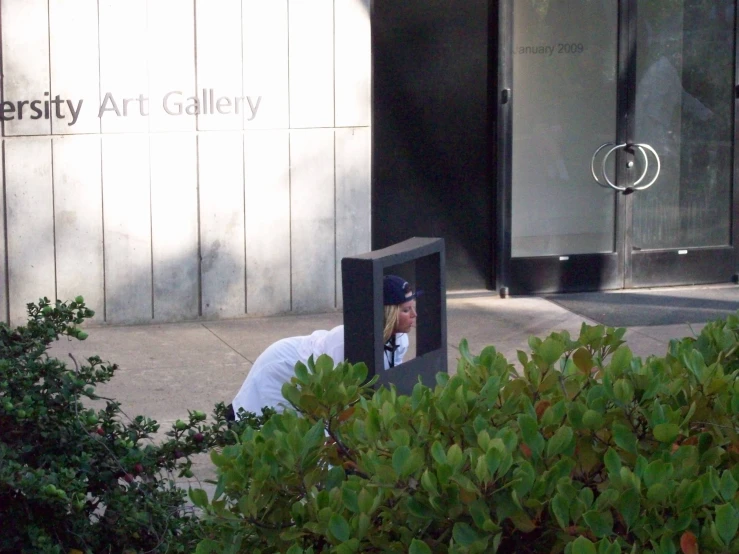 a woman laying down on the sidewalk in front of a building