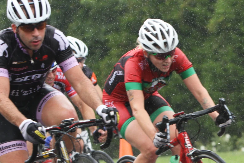 three men riding their bikes through the rain