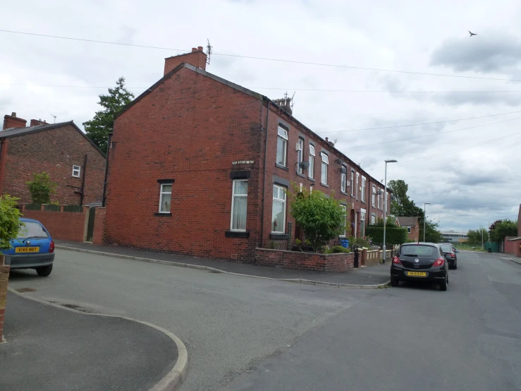 some cars parked in the street near a brick house