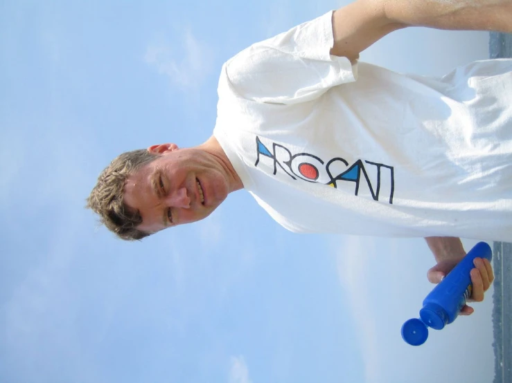 a man holding a blue frisbee standing on top of a sandy beach