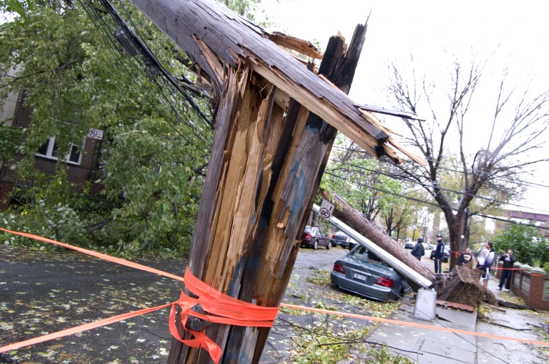 downed electrical poles and power lines are in front of a destroyed out - house