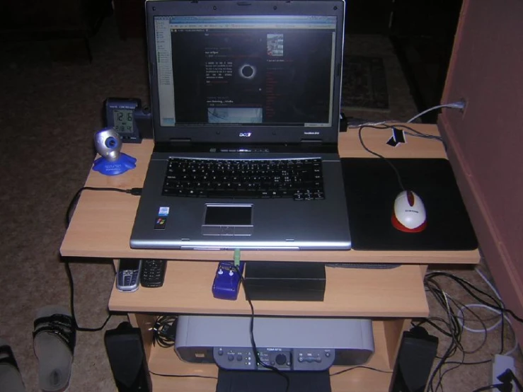 a laptop and other electronics on top of a wooden desk