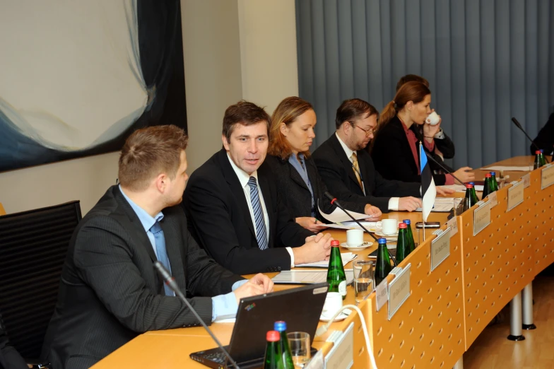 several people sitting at a table with papers and laptops