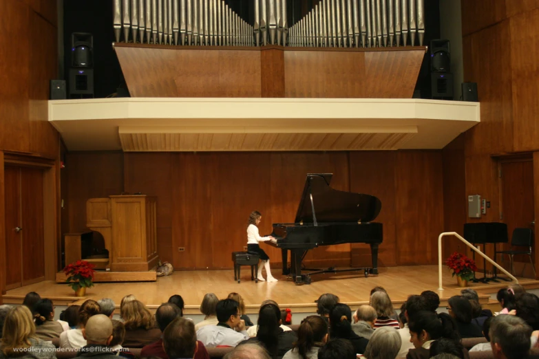 a young person sitting at a piano while people watch