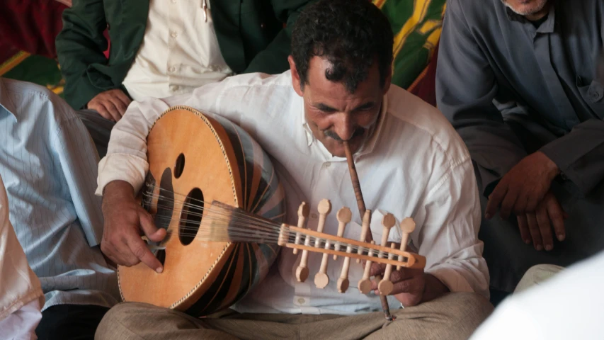 a man in white shirt holding a wooden instrument with strings