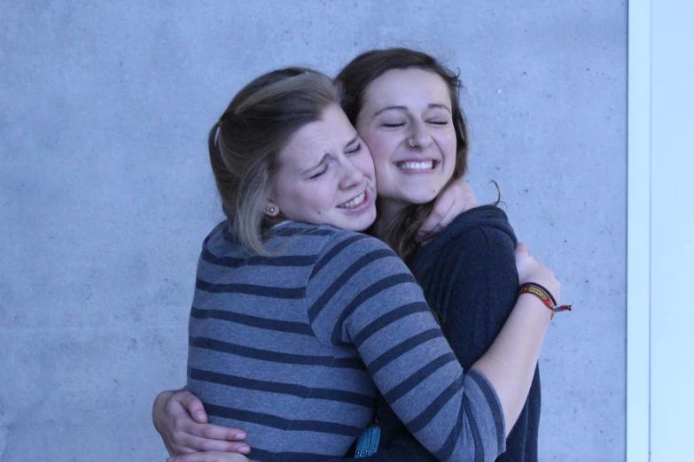 two women are hugging in an apartment courtyard