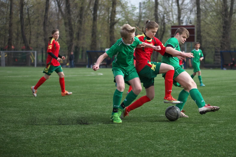 boys are on a field playing soccer in green and red