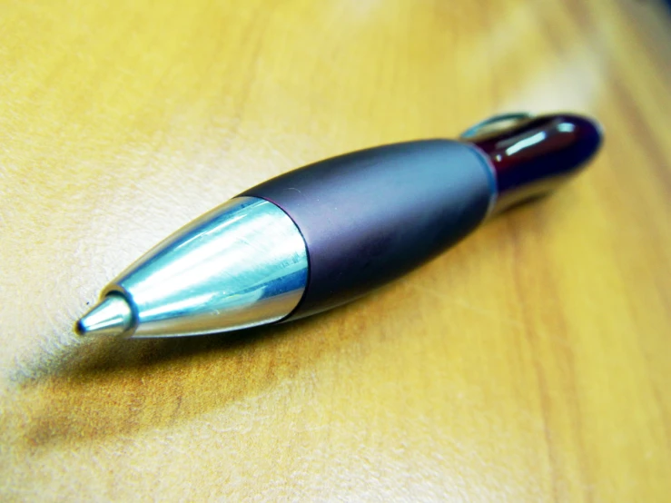 an artistic pen resting on a wood surface