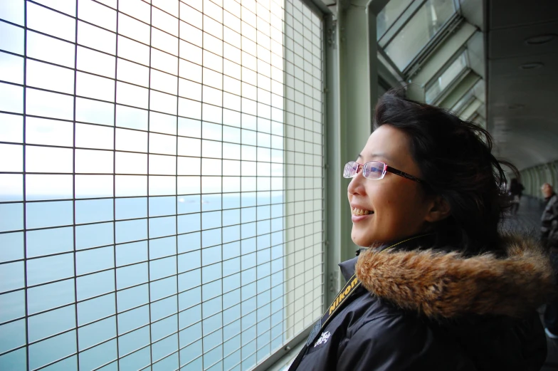 a woman in a fur lined hood near a window