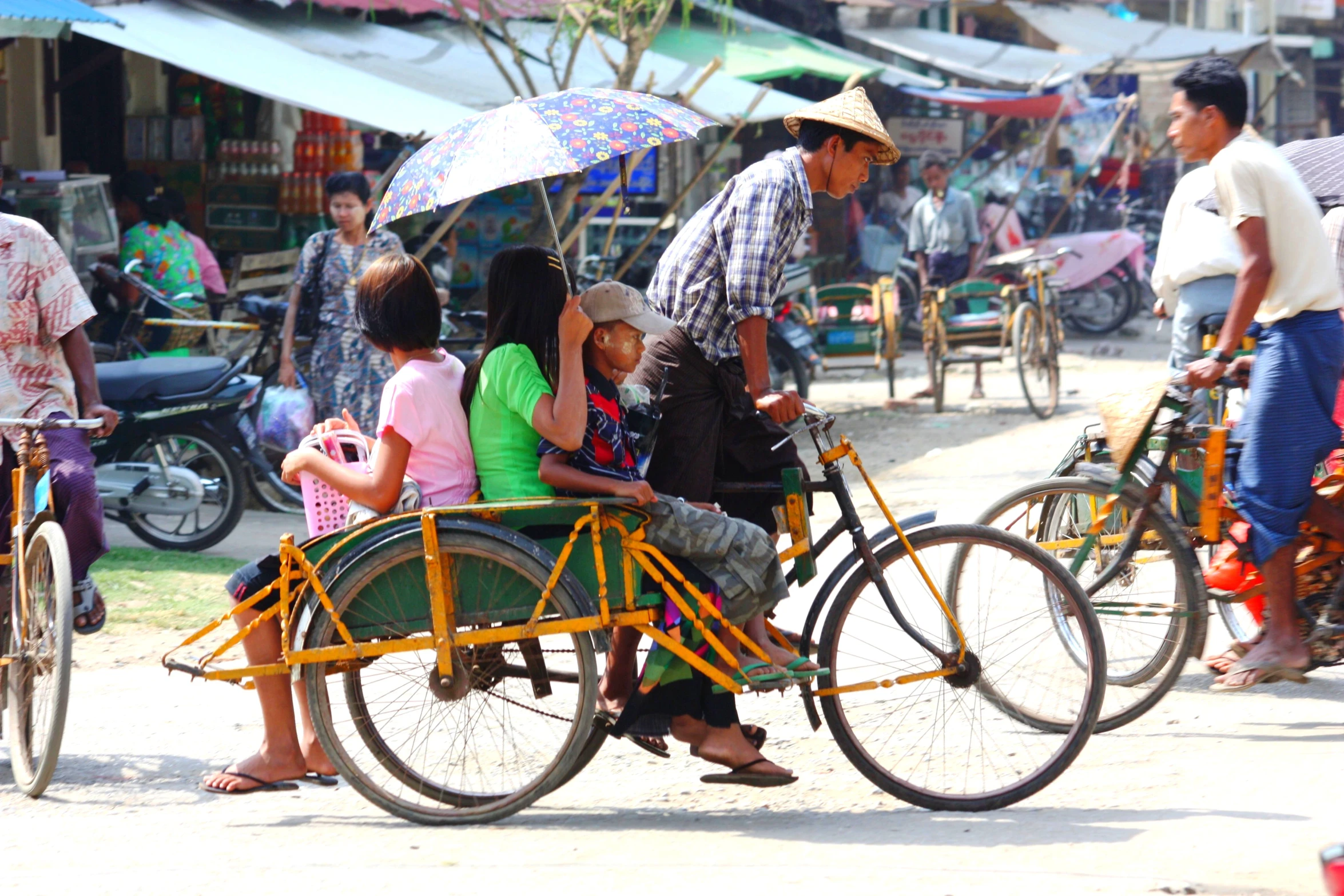 a family on a bicycle with umbrellas riding down the street