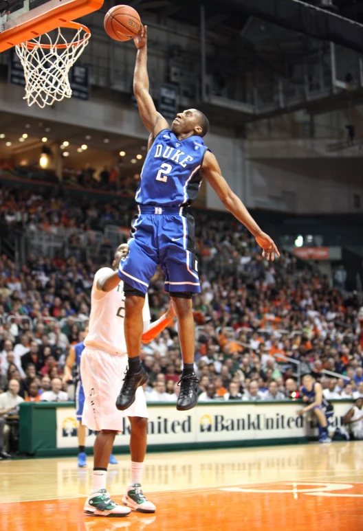 a man in a blue uniform is leaping up to dunk the basketball
