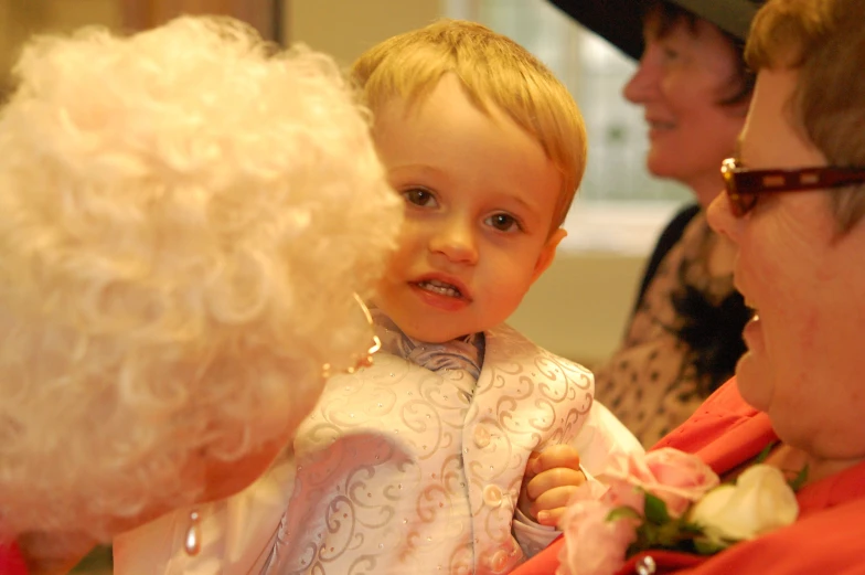 an older woman looks at the little boy's flower