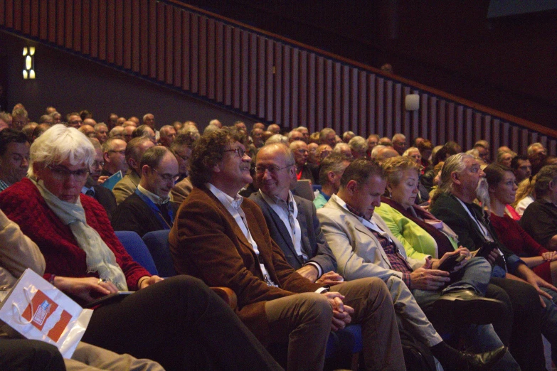 a number of people sit in rows, wearing jackets