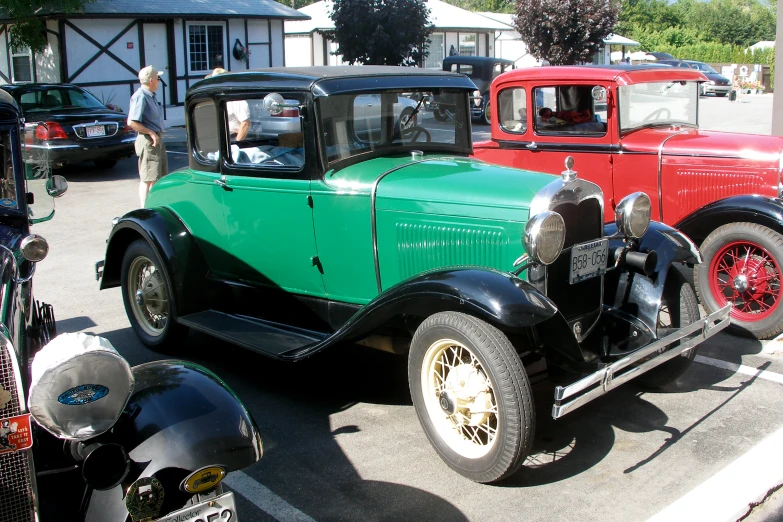 old time cars parked in a lot and one man looking at the car