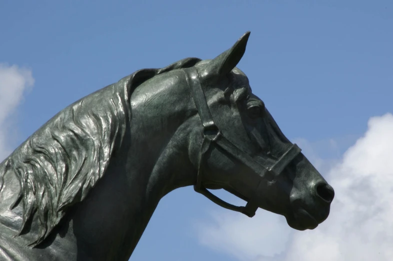 a metal horse head with a cloudy sky behind it