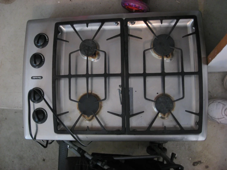 a stove top with four burners sits on a kitchen floor