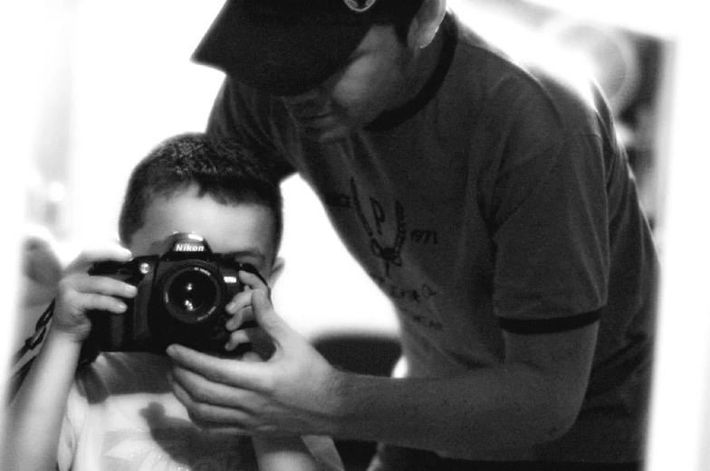 a black and white po of a man taking pictures with a boy holding a camera