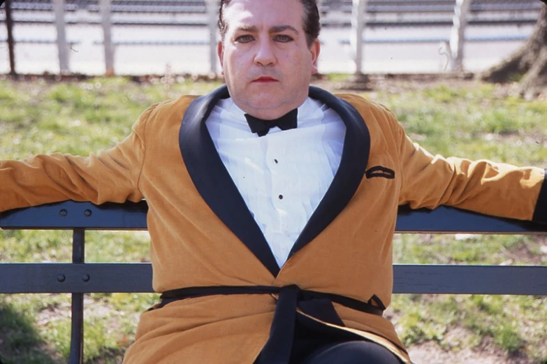 a man wearing a tuxedo sitting on a bench