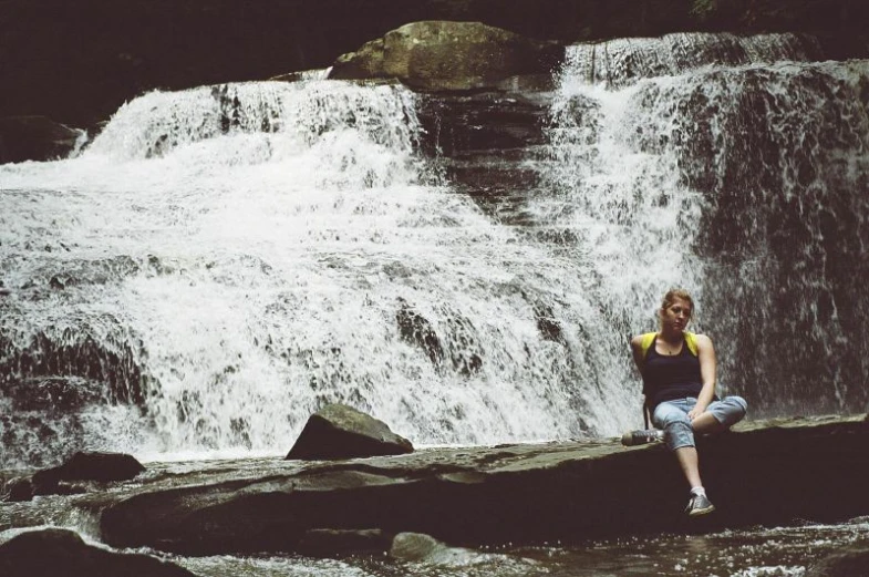 there is a woman sitting by the waterfall