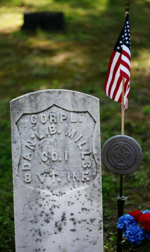 american flag sitting next to memorial stone with name and name on it