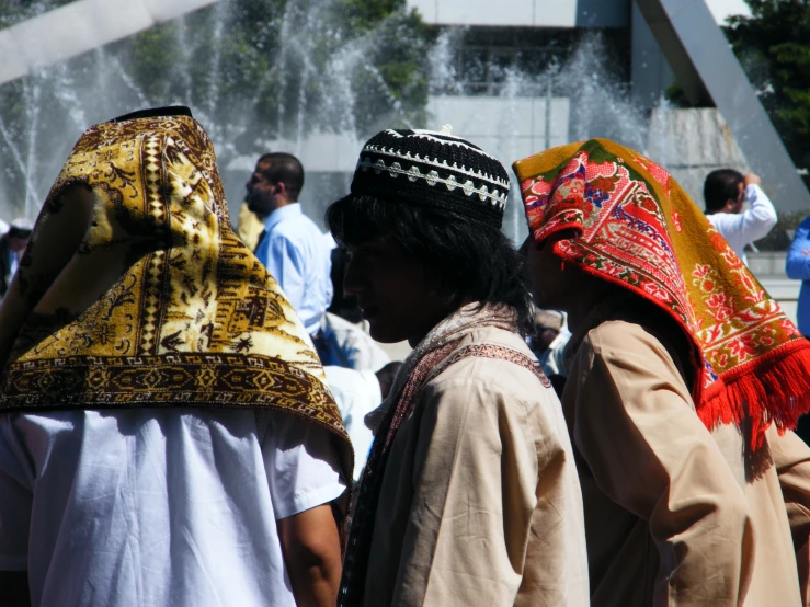 a group of men standing next to each other wearing colorful headscarves