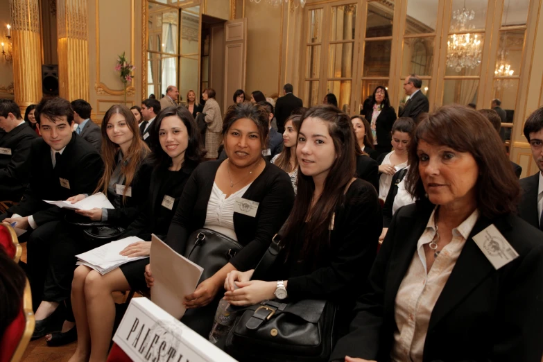 several women and men wearing suits are sitting together