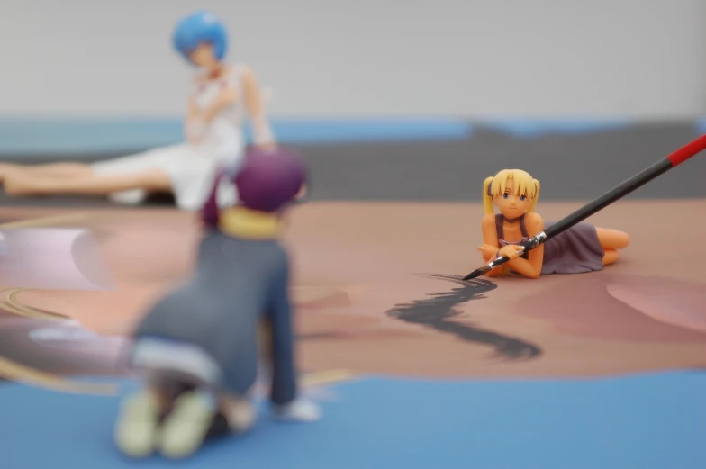 two anime figurines on the ground one is holding a sword and one is sitting on the ground