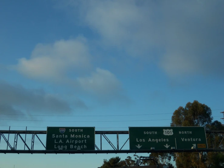 street signs above highway in california under cloudy sky
