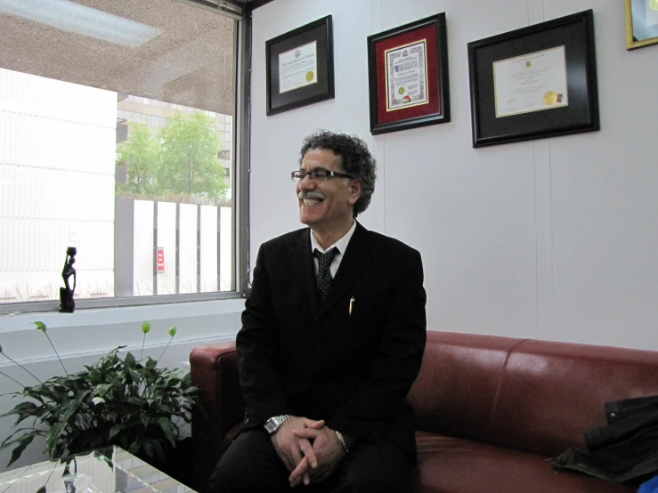 man sitting on a couch in front of an office window