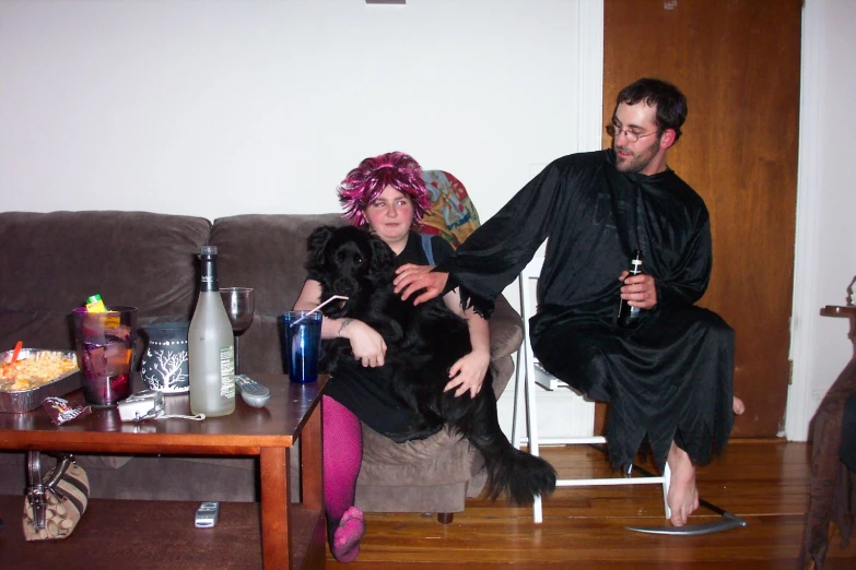 man sitting on sofa holding up lady with pink hair