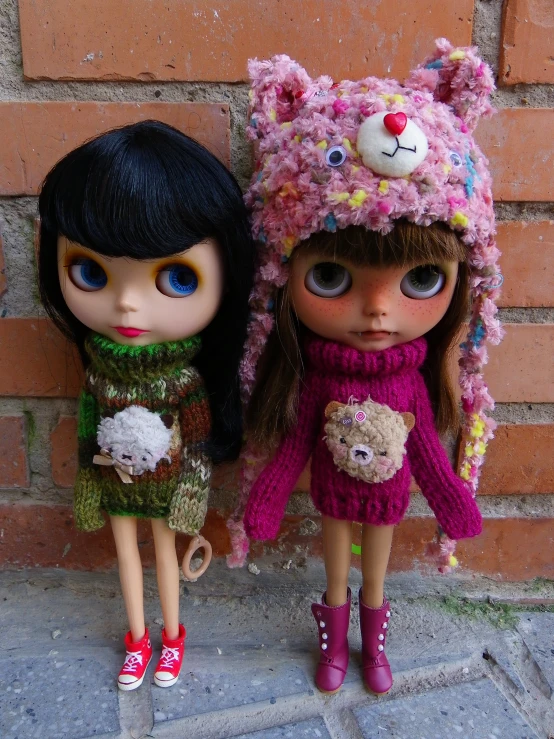 two dolls with knitted hats and one wearing sweater