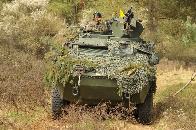 a tank with many people on top of it in the woods