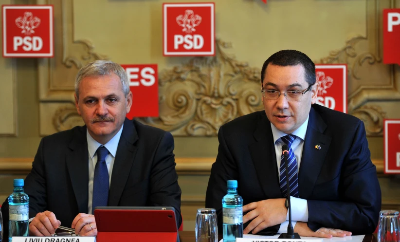 two men in suits and ties are sitting at a table