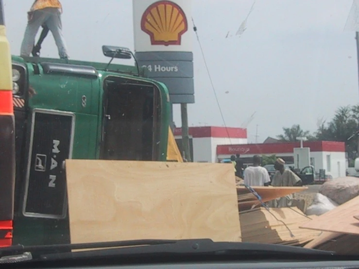 construction workers are seen on the roof of the shell gas station