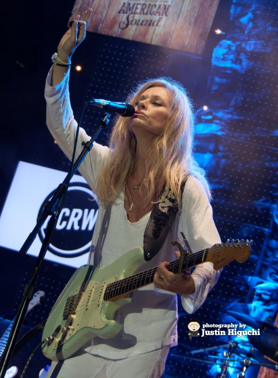 the woman is playing guitar in the stage