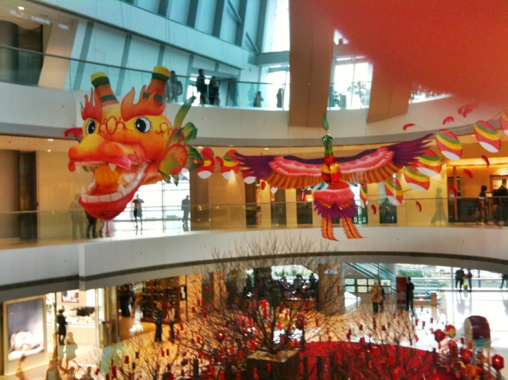 several dragon decorations in a mall lobby with lots of people
