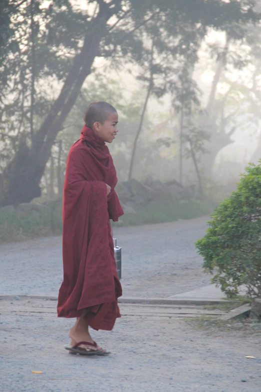 a buddhist monk walking down a dirt road in a park