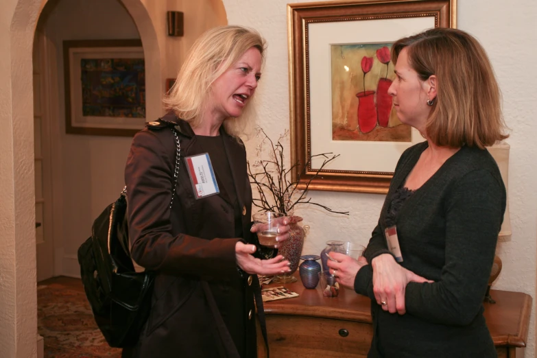 two women laughing as they talk and drink wine