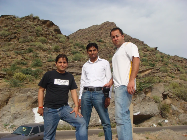 two men and a man standing together in front of a mountain