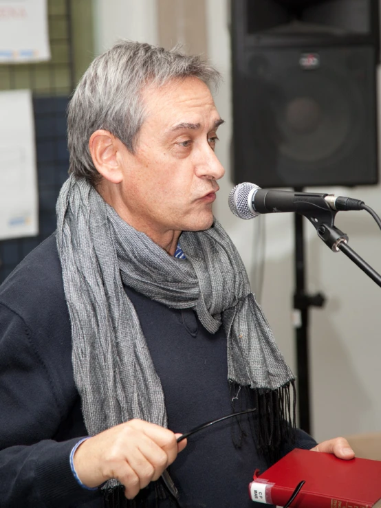 a person sitting in front of a microphone holding a red case