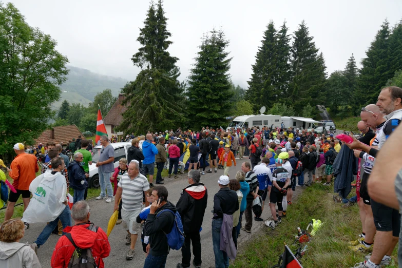 a crowd is walking down a dirt road in front of trees