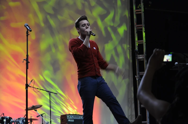 a young man on stage singing into a microphone