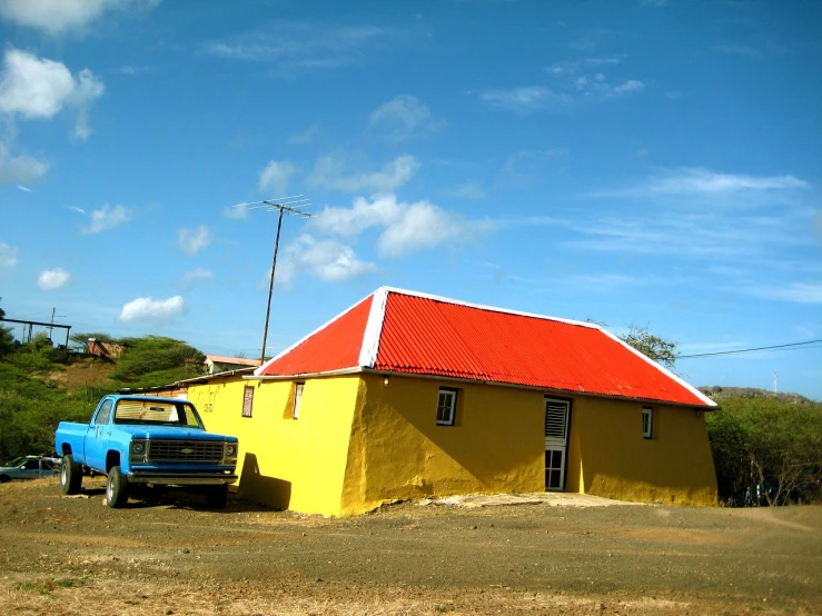 the bright yellow building and blue truck are parked in front