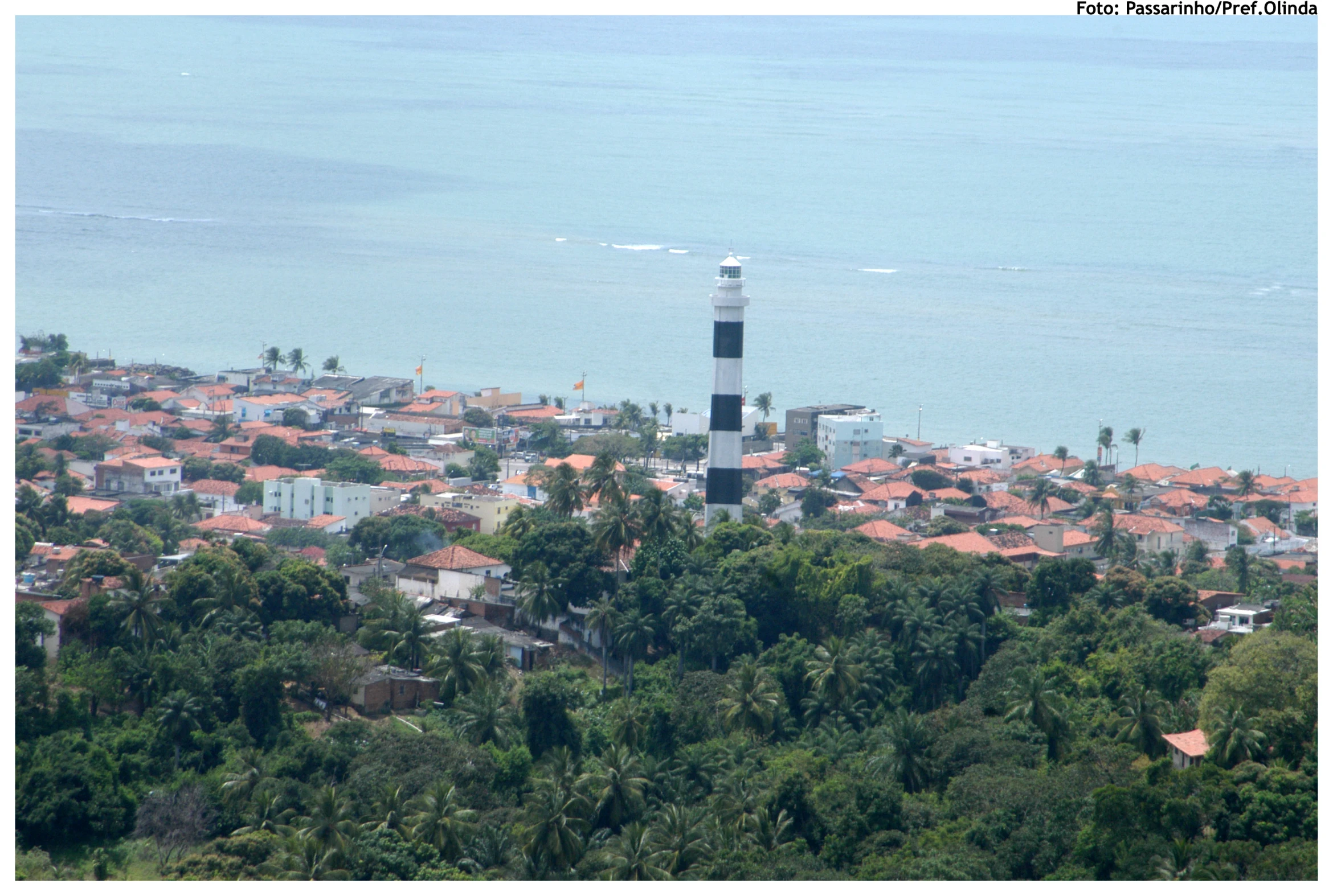 an aerial view of a town with water and a light tower